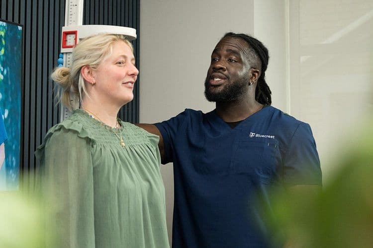 Bluecrest employee using a stadiometer to measure someone's height.