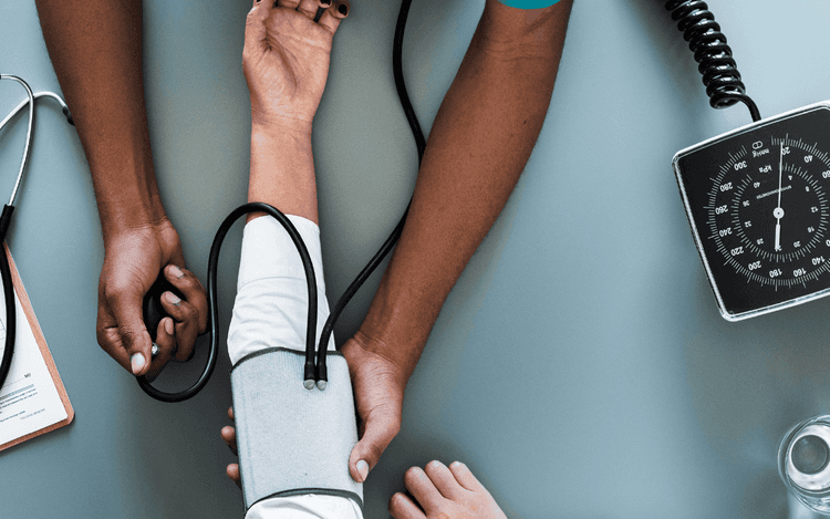 Blood pressure being taken from a cuff wrapped around an arm.